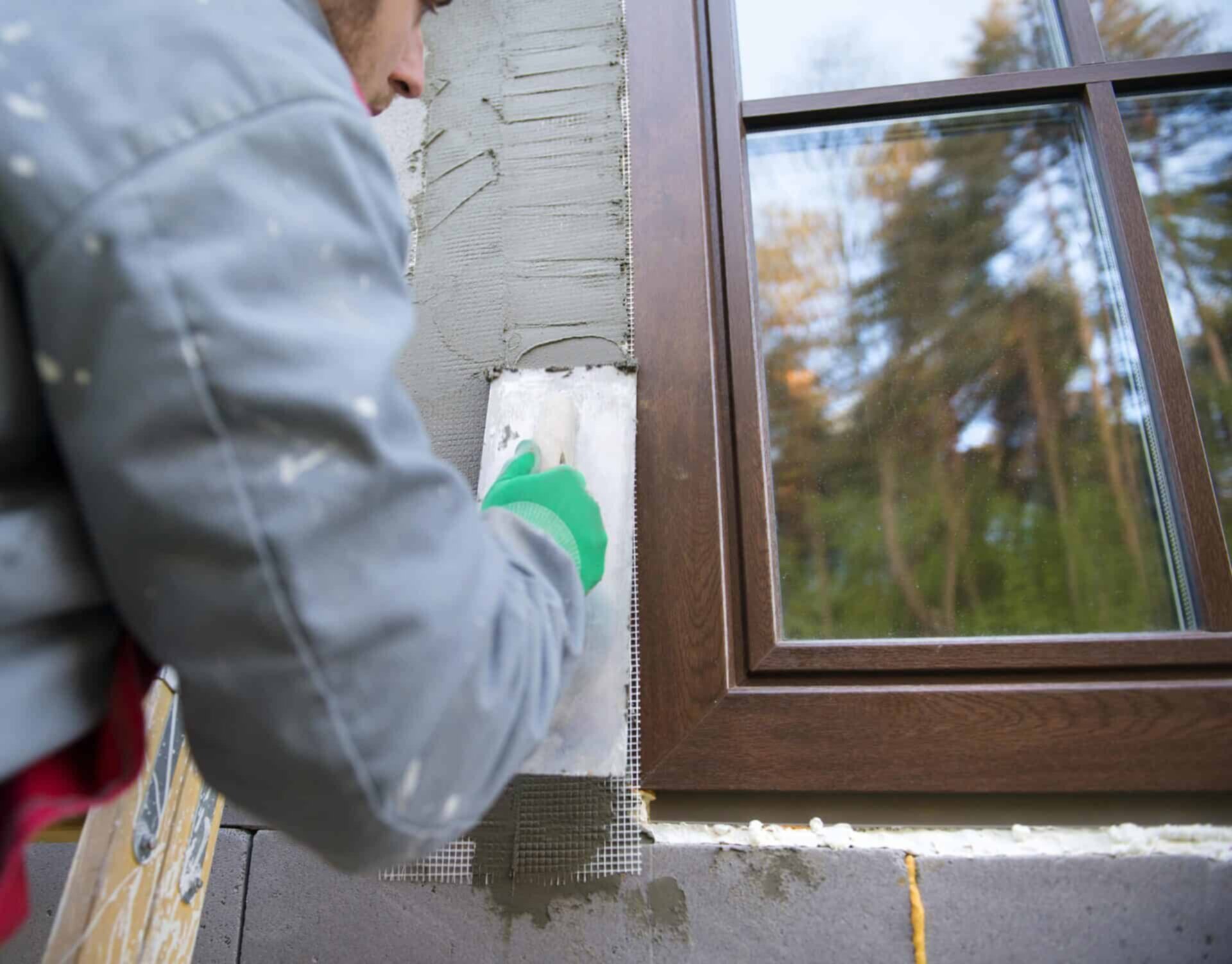 spreading out plaster with trowel around the windows after window replacement